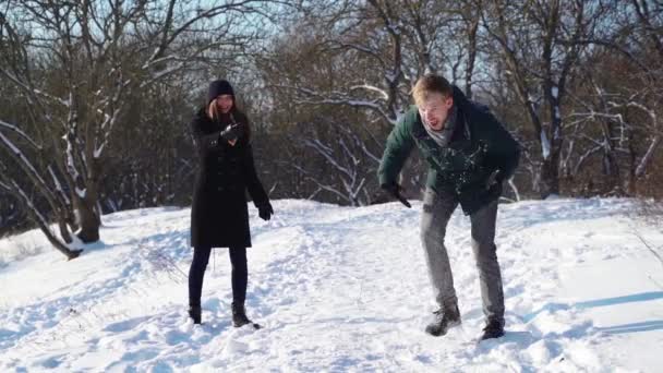 在冬天的森林里玩得开心的夫妻.微笑的男人和女人玩雪球 — 图库视频影像