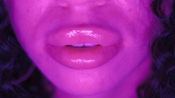 Boca feminina atraente e lábios em iluminação de néon roxo. Close-up. Movimento lento — Vídeo de Stock