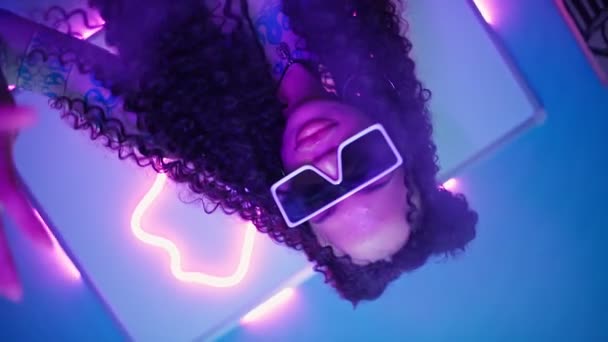 Schöne Frau in stylischen Gläsern, die im Neonlicht tanzt. Modell bewegt sich anmutig — Stockvideo