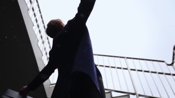 Успешный бизнесмен с поднятыми руками празднует свою победу во время снегопада — стоковое видео