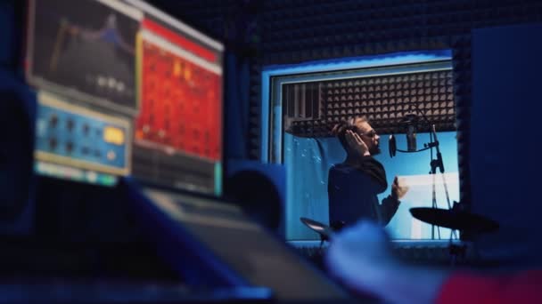 Мужчина рэп-певец с наушниками и звукоинженером записывают новую песню — стоковое видео