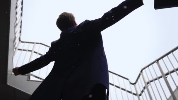 Empresário bem sucedido com mãos levantadas comemorando sua vitória durante a queda de neve — Vídeo de Stock