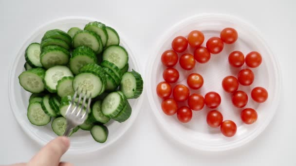 Människan på diet äter chilitomat och gurka från tallriken. Bantning och hälsosam mat — Stockvideo