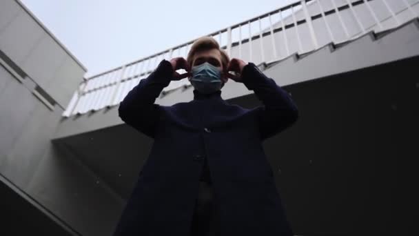 Üzgün genç adam kar yağarken yüzünün maskesini çıkarıyor. Coronavirüs. — Stok video