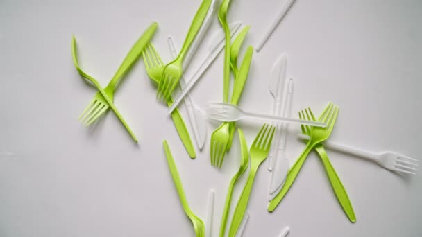 Lots plastic forks and eating utensils are falling on white background. — Stock Video
