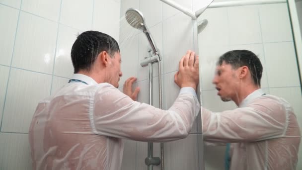 Triste homme en chemise et cravate se tient dans la salle de bain sous la douche et les bains dans les vêtements — Video