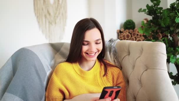 Femeia zâmbind ține Smartphone vizionarea Povești Social Media Video Sit pe canapea — Videoclip de stoc