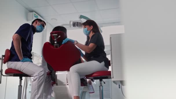 Une dentiste professionnelle en gants médicaux examine une patiente dans une clinique dentaire — Video