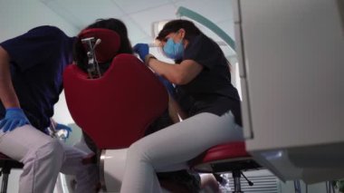 Diş hekimleri kadın ve erkek doktor maskeli hastalara diş sağlığı kliniğinde hizmet veriyor.