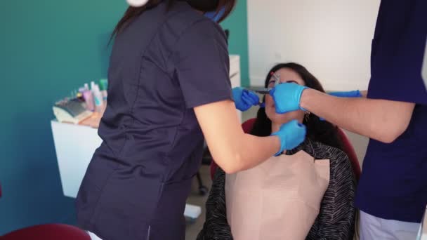 Dentista en guantes médicos usando herramienta especial examina paciente en clínica dental — Vídeo de stock