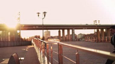 Ceketli ve kravatlı bir iş adamı arka plandaki günbatımı ışığında bir engelin üzerinden atlar.