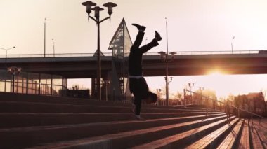 Ceketli ve kravatlı bir iş adamı amuda kalkarak merdivenlerden iniyor. gün batımı ışığı