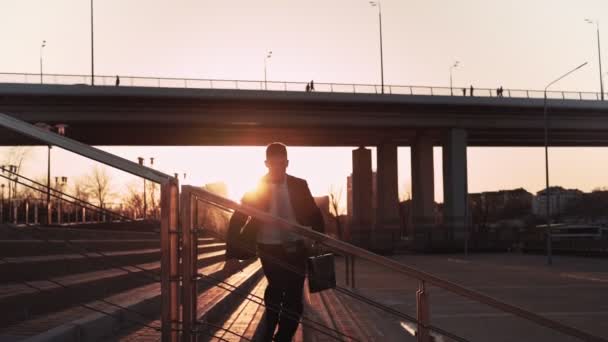 Zakenman in jas en das springt over een obstakel op de achtergrond zonsondergang licht — Stockvideo