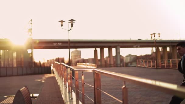 Businessman in jacket and tie jumps over an obstacle on background sunset light — Wideo stockowe