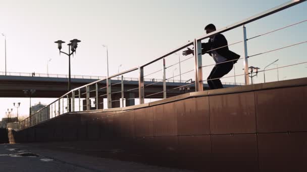 Businessman in jacket and tie jumps over an obstacle on background city — Stock video