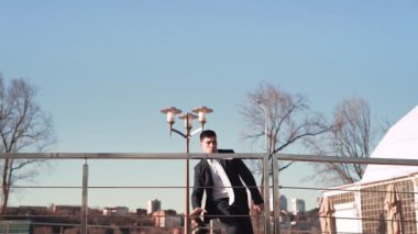 Ceketli ve kravatlı bir iş adamı elinde bavuluyla bir engelin üzerinden atlar.