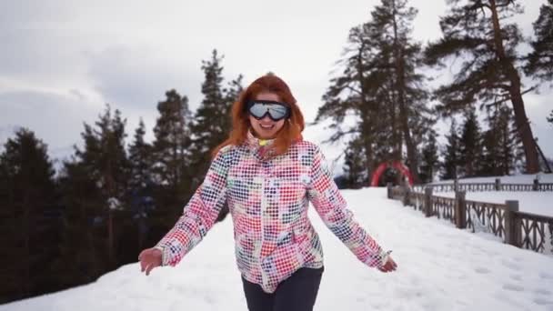 Glad flicka i skidutrustning körs och leenden av snöiga berg och skog — Stockvideo
