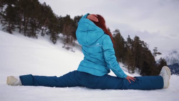 Chica en el equipo de esquí se sienta en divisiones contra el telón de fondo Montaña Invierno — Vídeos de Stock