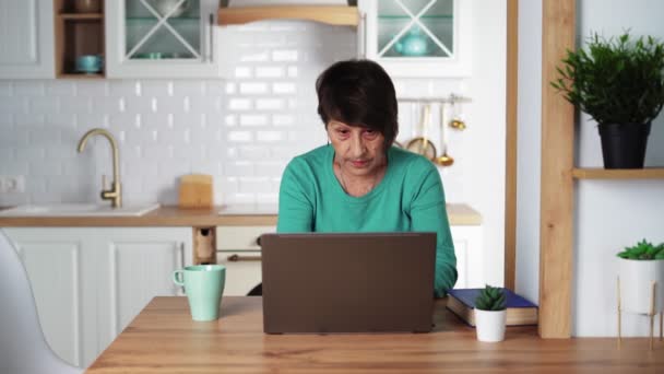 Äldre fokuserad kvinna fjärrarbetar på laptop hemma. Äldre personer — Stockvideo