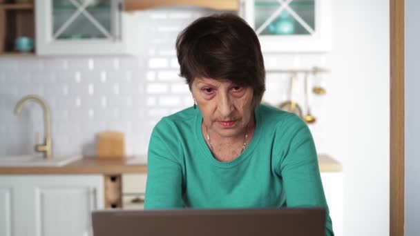 Oudere gefocuste vrouw die thuis op een laptop werkt. Ouderen — Stockvideo