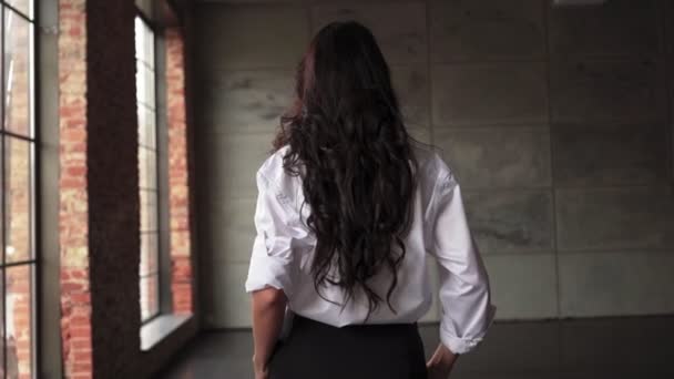 Felismerhetetlen barna üzletasszony fehér ingben sétál át az irodán. — Stock videók