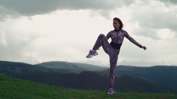 Mujer atlética que se extiende contra el impresionante paisaje de montaña. Chica haciendo divisiones — Vídeo de stock