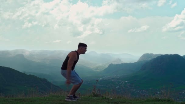 Atlétikai ember végez egy hátraszaltó mutatvány ellen egy lenyűgöző hegyi táj — Stock videók