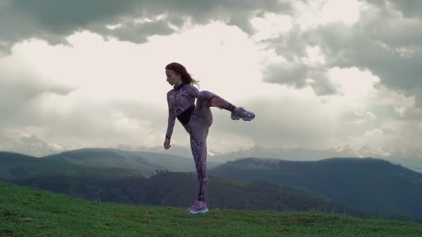 Спортивная женщина растягивается против потрясающего горного ландшафта. Девочка, делающая сплиты — стоковое видео