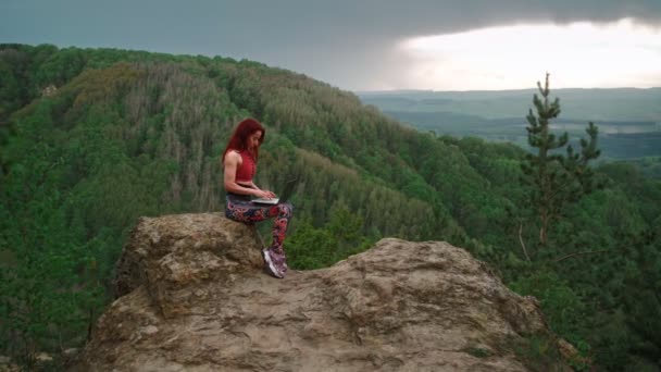 Mujer freelancer trabaja portátil en la cima montaña telón de fondo impresionante montaña — Vídeos de Stock