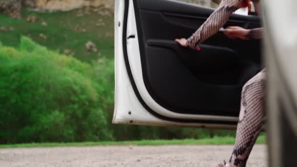 Женщина-путешественница выходит из машины и поднимает руки на фоне красивой горы — стоковое видео