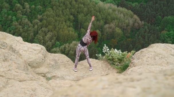 Αθλητική γυναίκα ασκεί γιόγκα στην κορυφή του βουνού. Λεπτό κορίτσι πηγαίνει σε αθλήματα σε εξωτερικούς χώρους — Αρχείο Βίντεο