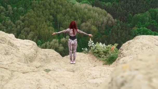 Спортивная девушка практикует йогу на краю горы. Тренировки стройных женщин на открытом воздухе — стоковое видео