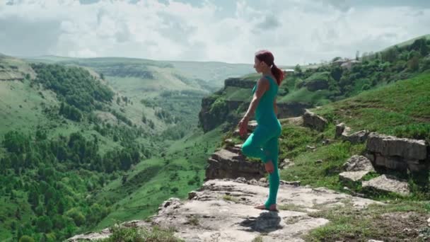Αθλητικό κορίτσι προπονείται γιόγκα στην άκρη του βουνού. Λεπτή γυναίκα προπόνηση σε εξωτερικούς χώρους — Αρχείο Βίντεο