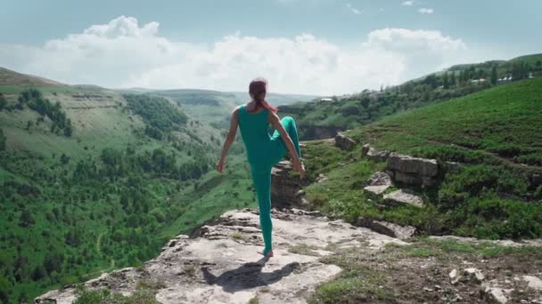 Αθλητική γυναίκα που απλώνεται ενάντια στο εκπληκτικό ορεινό τοπίο. Κορίτσι που κάνει σχισμές — Αρχείο Βίντεο