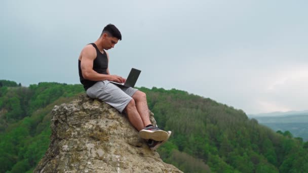 Beau travail de l'homme sur ordinateur portable sur la montagne sur fond incroyable emplacement naturel — Video