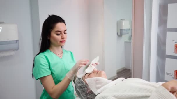 Mujer esteticista hace que el tratamiento facial de la piel paciente femenina en el salón de belleza — Vídeos de Stock