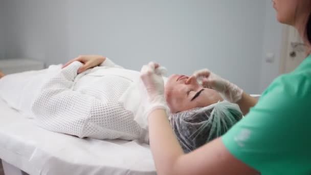 Woman beautician makes procedures facial cleans patient. Spa skin and body care — Stock Video