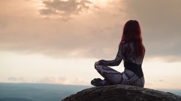 Smukła dziewczyna siedzi w pozycji lotosu na szczycie góry podczas pięknego zachodu słońca — Wideo stockowe