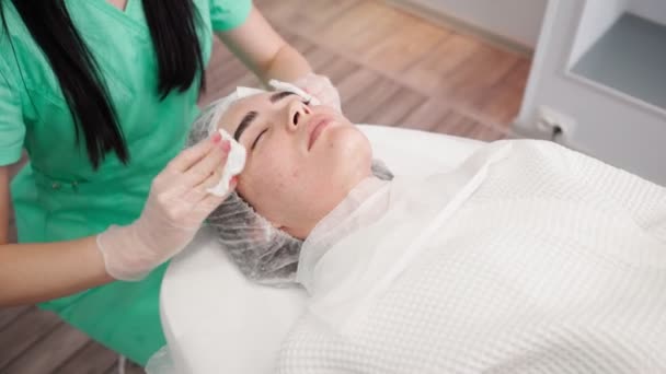 Mujer esteticista hace que el tratamiento facial de la piel paciente femenina en el salón de belleza — Vídeo de stock