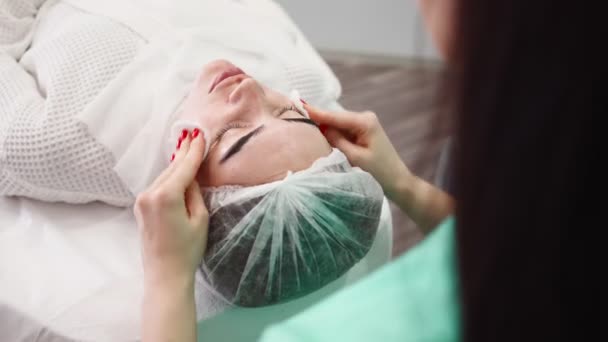 Kobieta kosmetyczka sprawia, że zabieg pielęgnacji skóry twarzy pacjentka w salonie piękności — Wideo stockowe