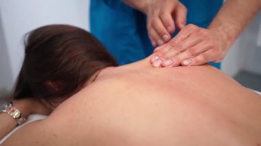 Erkek profesyonel masör, spa salonundaki zayıf bir kıza masaj yapıyor..