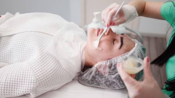 Жінка-косметолог робить процедури очищення обличчя пацієнтом. Спа шкіра і догляд за тілом — стокове відео