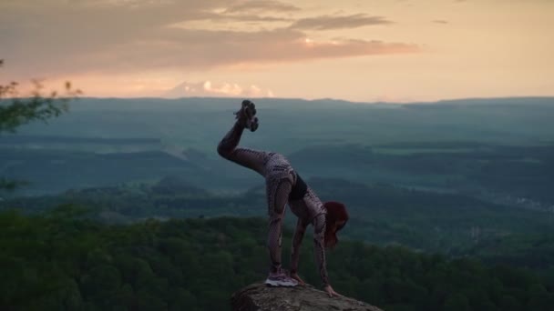 Athletische Frau streckt sich vor atemberaubender Berglandschaft. Mädchen macht Spagat — Stockvideo