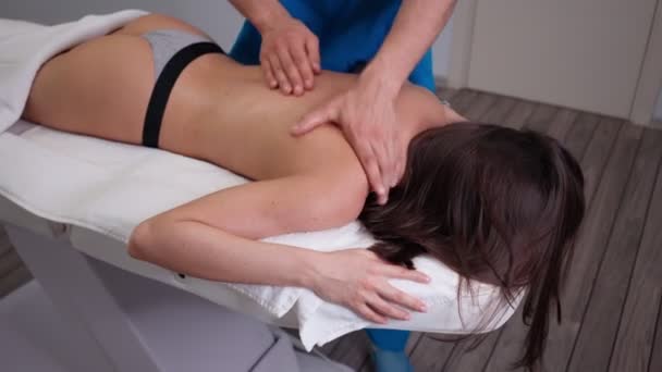Чоловічий професійний масажист робить масаж красивій дівчині клієнт в салоні краси — стокове відео