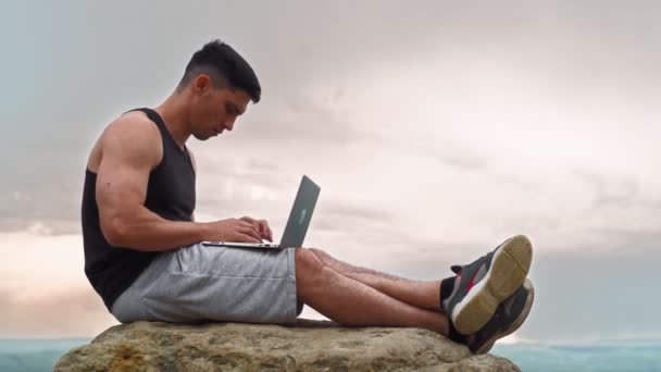Przystojny człowiek pracuje na laptopie w górach na tle niesamowite naturalne położenie — Wideo stockowe