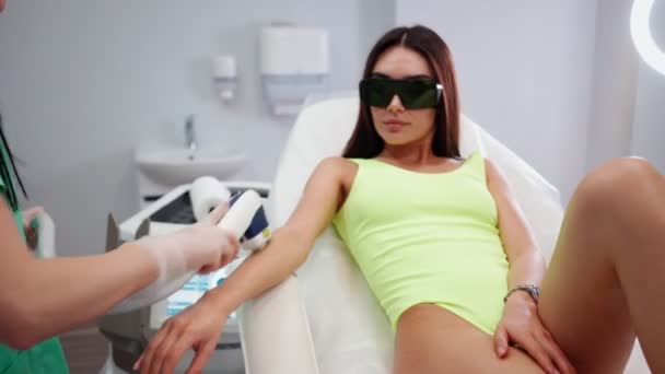 Beautiful girl in beauty salon makes laser hair removal procedure on her hands — Stock Video