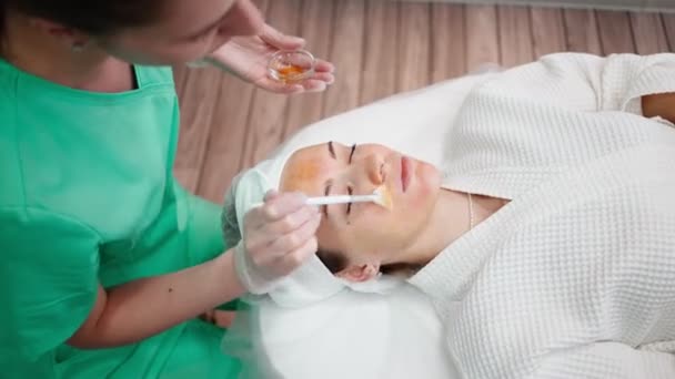 Dívka krása dělá obličej čištění procedura pro mladou ženu v salonu krásy — Stock video