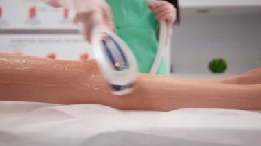 Güzellik uzmanı kadın, lazer tüy kesme, kadın bacakları güzellik salonu prosedürünü uyguluyor.