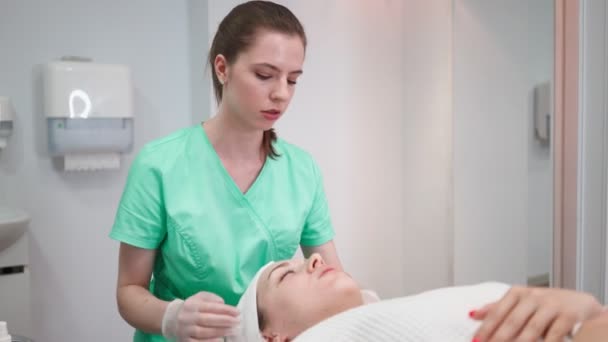 Girl Beautician Makes Facial Cleansing Procedure for Young Woman in Beauty Salon — Stock Video