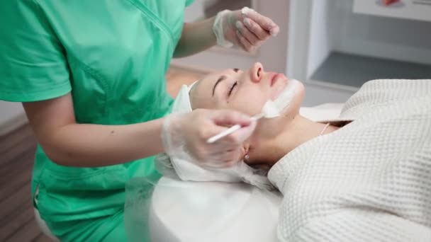 Girl Beautician Makes Facial Cleansing Procedure for Young Woman in Beauty Salon — Stock Video